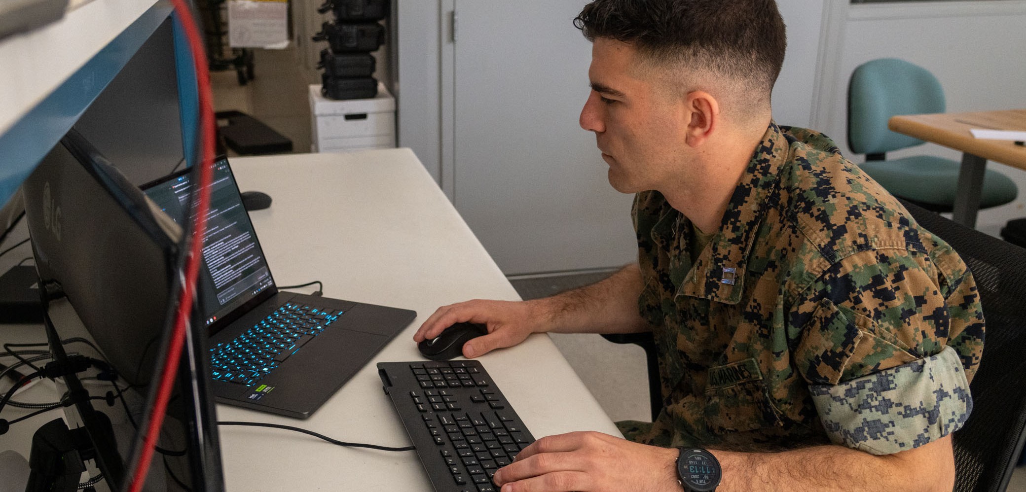 Naval Postgraduate School computer science student U.S. Marine Corps Capt. Kyle Hicks reviews code for an artificial intelligence powered program management tool he developed in support of a collaborative research project on low cost missile design.