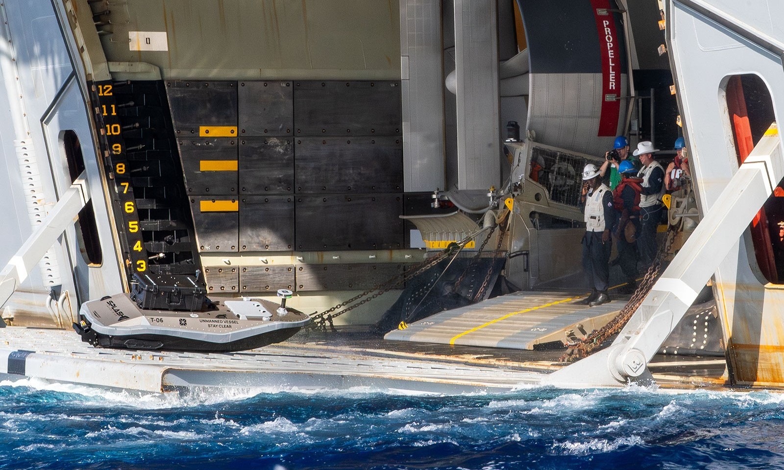 A digitally crewed surface vessel (DCSV) enters the well deck of the amphibious assault ship USS Essex (LHD 2) during a logistics demonstration.